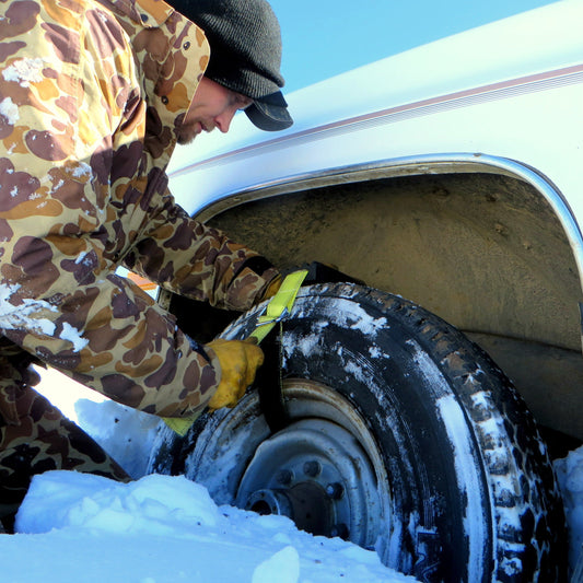 Two tires with snow chains and a green carrying bag on a white background