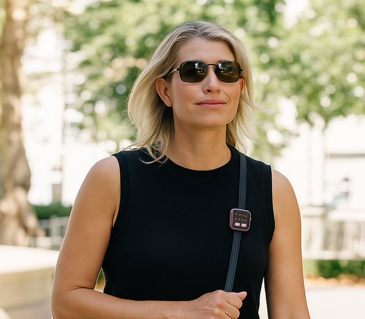 Woman wearing sunglasses and a black sleeveless top with a blurred outdoor background