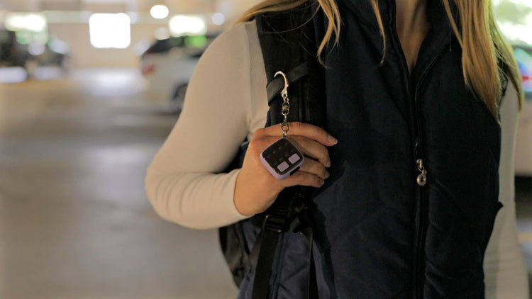 Person holding a black bag with a keychain attached, blurred background
