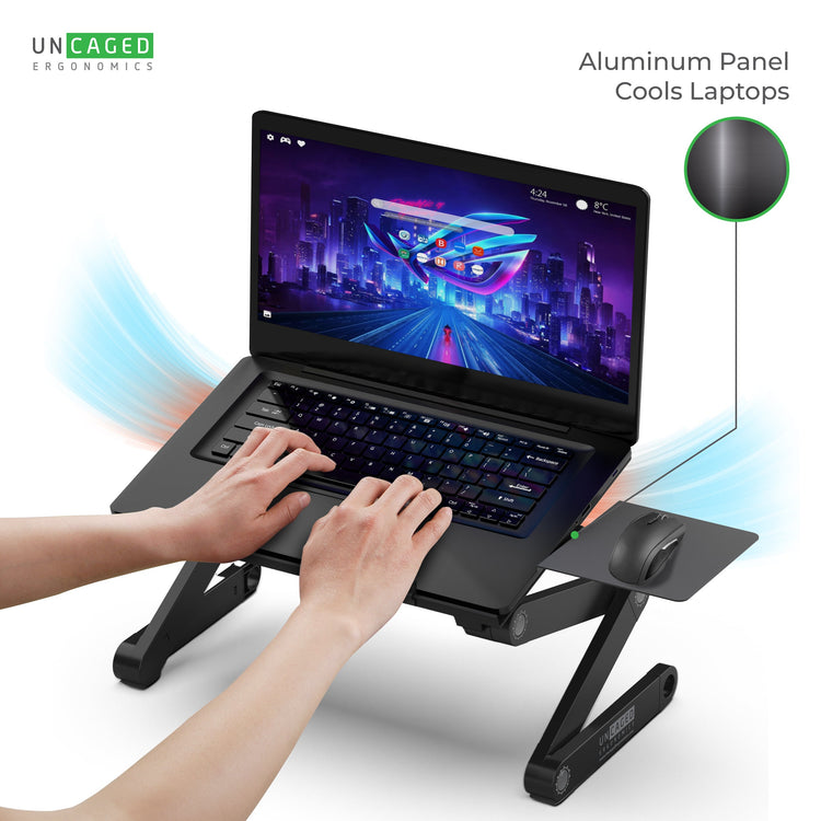 Laptop on a cooling stand with hands typing, featuring 'UNCAGED' branding.