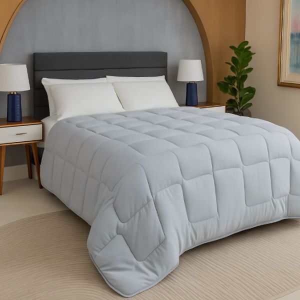 Gray comforter on a bed in a bedroom setting with lamps and decor.
