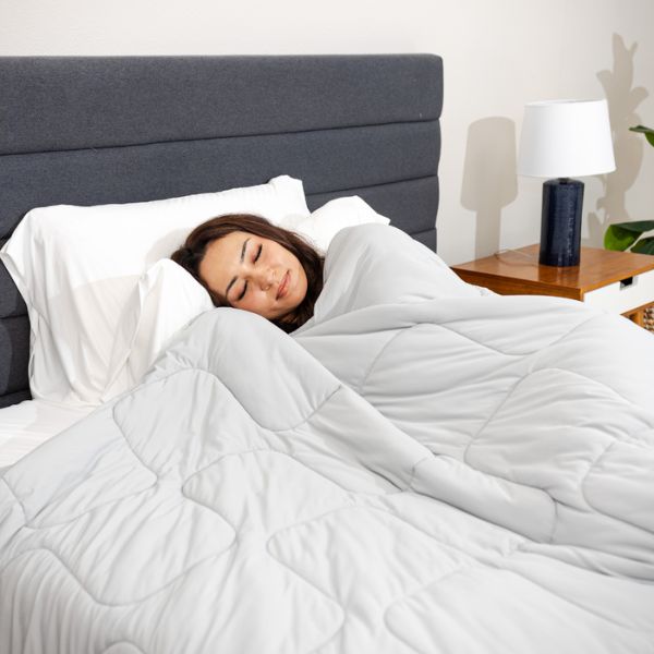 Woman sleeping under a white comforter in a bedroom setting.