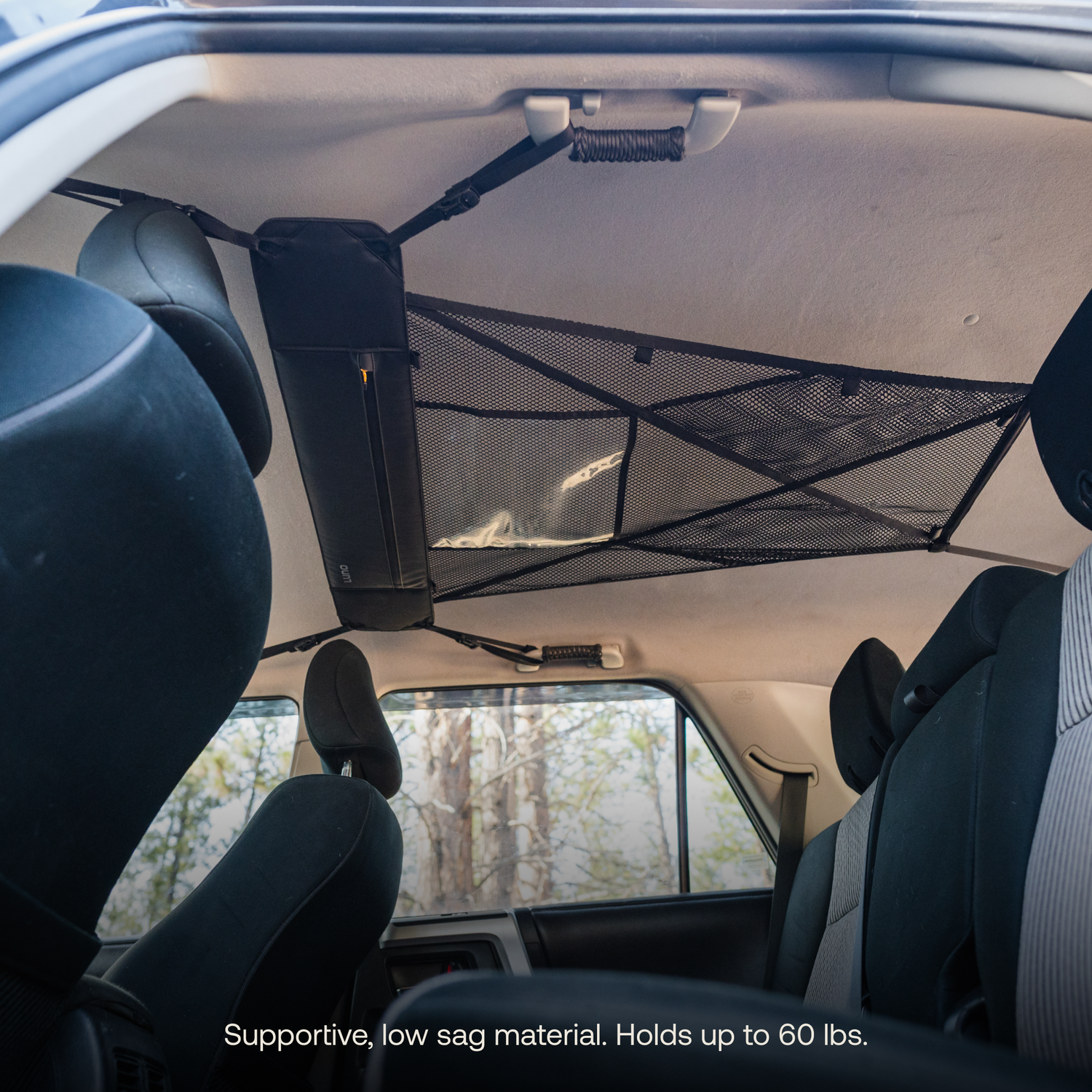 View of a car interior showcasing the Luno® Cargo Hammock attached to the roof between the front and rear seats. The supportive, low sag material of this portable gear shelf is designed to hold up to 60 lbs, making it perfect for your adventure mobile's gear storage needs.
