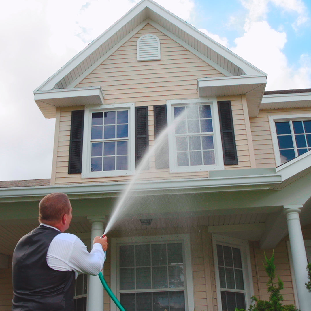 Person using a hose to clean the exterior of a house