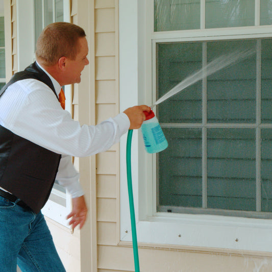 Person using a hose to clean the exterior of a house