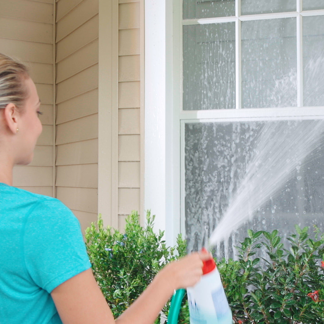 Person cleaning a window with a spray bottle outdoors.