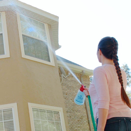 Person using a hose to clean the exterior of a house