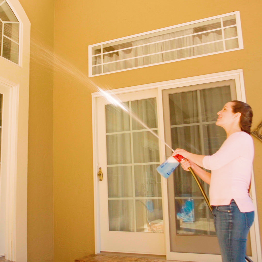 Person cleaning a window with a squeegee in a room with yellow walls and a white door.
