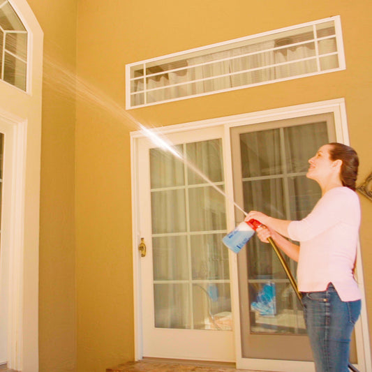 Person using a hose to clean the exterior of a house