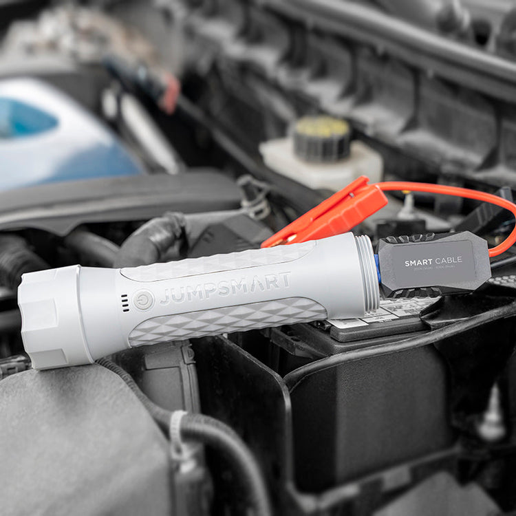 Jump starter device on a car battery with 'JumperCar' branding.