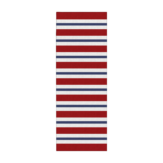 Wooden bench with decorative pillows on a porch featuring a red, white, and blue striped rug.