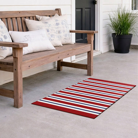 Wooden bench with decorative pillows on a porch featuring a red, white, and blue striped rug.