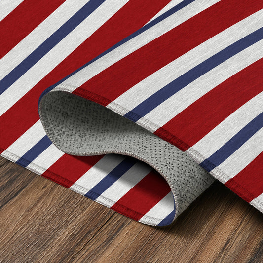 Wooden bench with decorative pillows on a porch featuring a red, white, and blue striped rug.