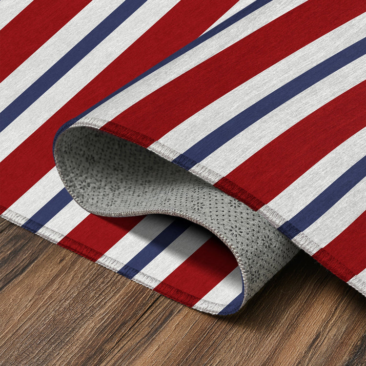 Striped rug with red, white, and blue colors on a wooden floor.