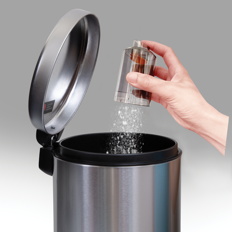 Hand pouring a small container of salt into a silver trash can with a gray background