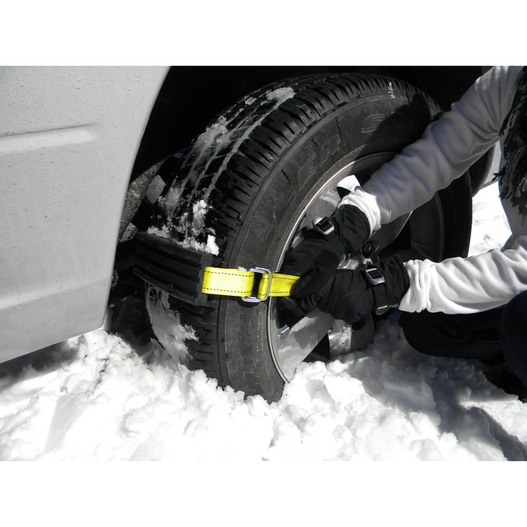 Person securing a snow tire chain on a car tire in snowy conditions